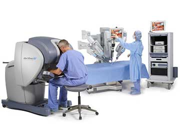 Surgeon in front a machinery, connected to another machinery placed above a medical bed in a medical theatre. A nurse is observing the machinery above the bed.